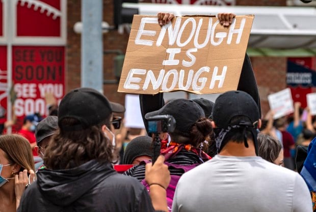 Image of protestor holding up a sign that says Enough is Enough